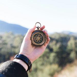 person holding compass selective focus photography